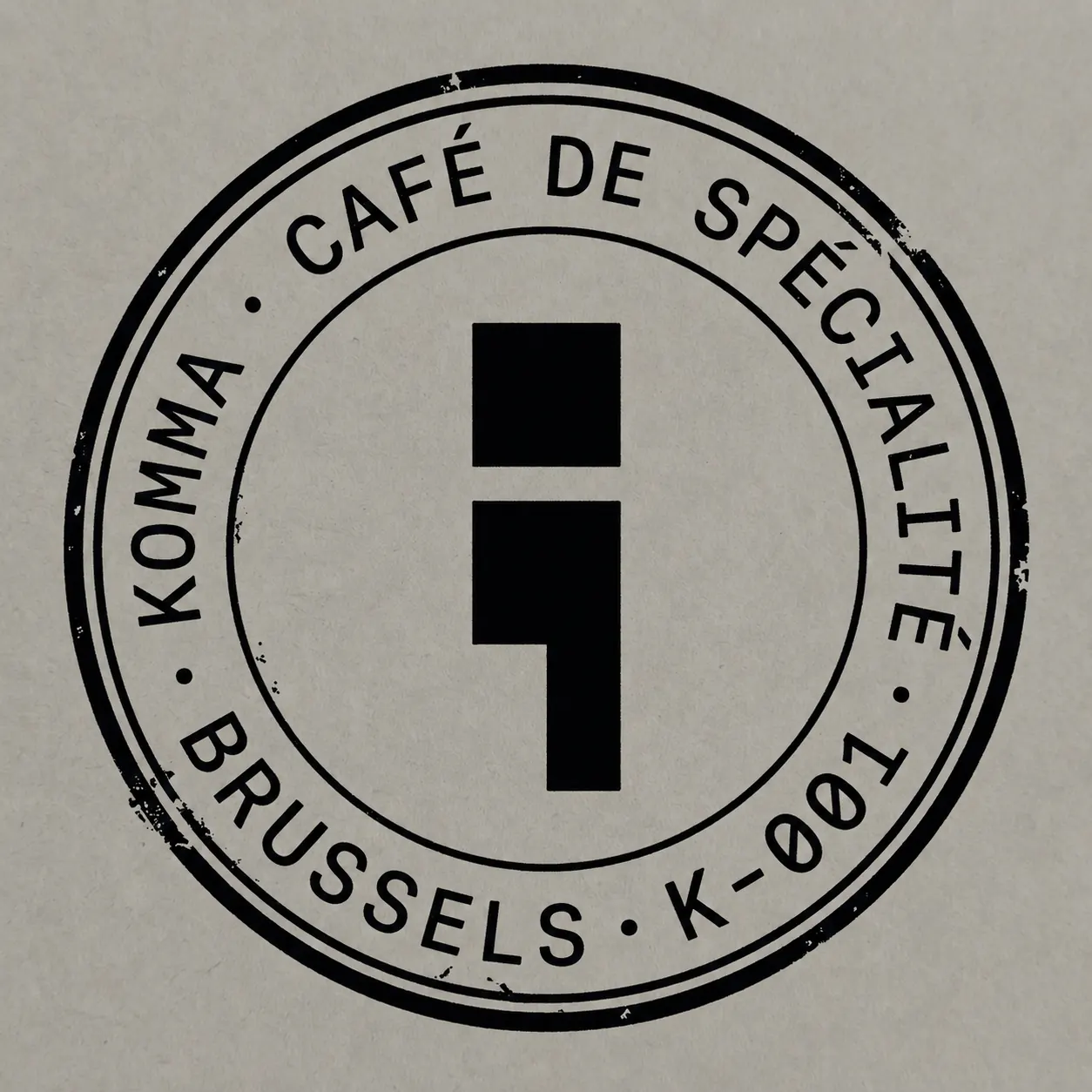 Tampon encreur circulaire KOMMA · CAFÉ DE SPÉCIALITÉ · BRUSSELS · K-001, avec virgule géométrique au centre.